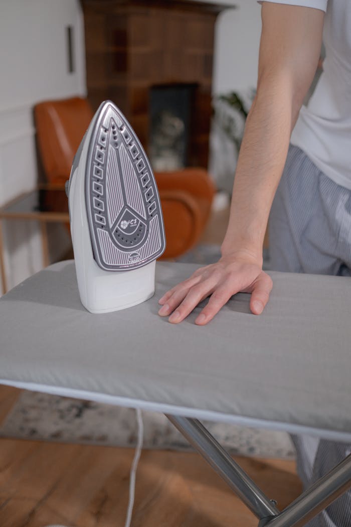 A person ironing clothes on an ironing board, adding warmth and comfort to home chores.