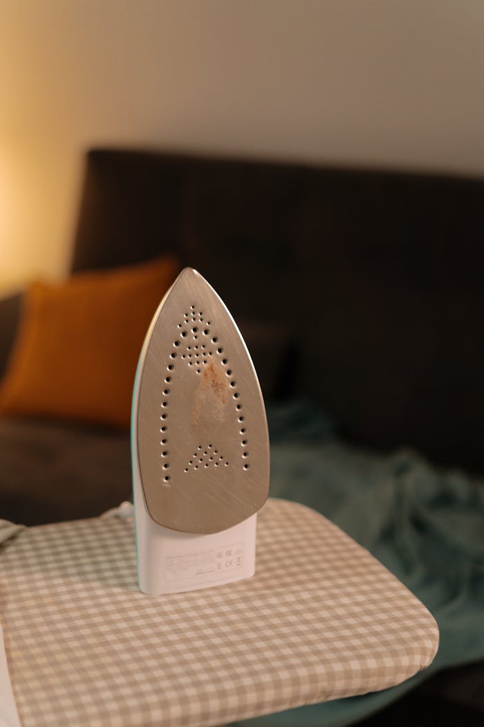 Modern clothes iron on an ironing board in a cozy indoor setting with warm lighting.